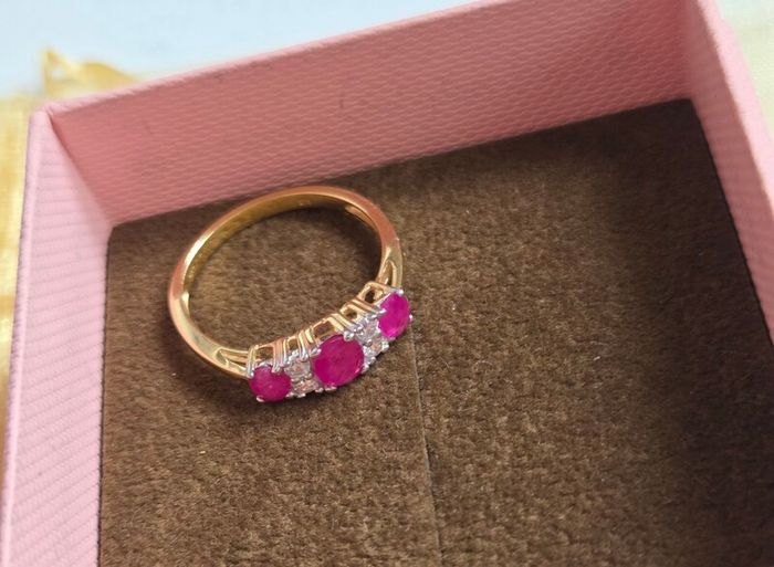 Beautiful yellow gold ring featuring three stunning rubies surrounded by sparkling cubic zirconia stones. Size M, in beautiful condition.