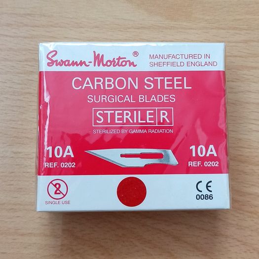 Box of Swann-Morton carbon steel sterile surgical blades manufactured in Sheffield, England, containing 100 individually foil-peel-packed blades protected with VPI