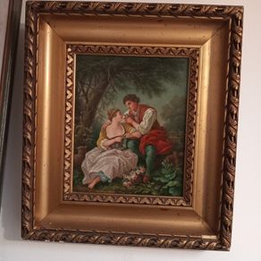 Gilt framed painting of a couple in rural scene.