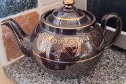 Antique dark brown glazed teapot featuring gold coloured arabesque and floral detailing. Resembles the classic 'Brown Betty'