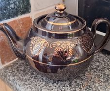 Antique dark brown glazed teapot featuring gold coloured arabesque and floral detailing. Resembles the classic 'Brown Betty'