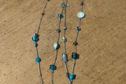 long necklace featuring a mix of blue-toned glass beads and silver-colored accent beads on a thin gray cord