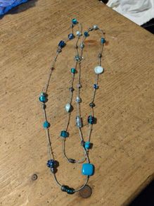 long necklace featuring a mix of blue-toned glass beads and silver-colored accent beads on a thin gray cord