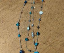 long necklace featuring a mix of blue-toned glass beads and silver-colored accent beads on a thin gray cord
