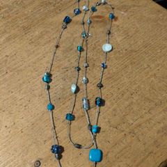 long necklace featuring a mix of blue-toned glass beads and silver-colored accent beads on a thin gray cord