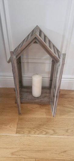 Rustic house-shaped wooden lantern featuring glass panel doors and a pitched roof design