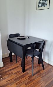 Black drop-leaf dining table with two chairs