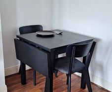 Black drop-leaf dining table with two chairs