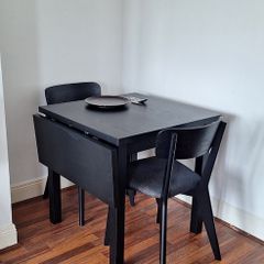 Black drop-leaf dining table with two chairs