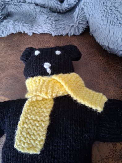 Hand knitted black teddy bear with yellow scarf
