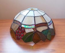 Vintage Tiffany-style stained glass lampshade featuring a bunch  of red grapes set against a cream-colored background with green and brown leaves