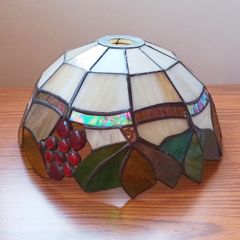 Vintage Tiffany-style stained glass lampshade featuring a bunch  of red grapes set against a cream-colored background with green and brown leaves