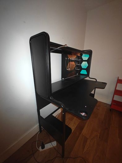 Black gaming desk with integrated pegboard and shelf