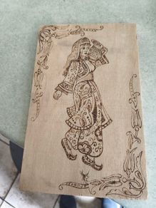 a piece of wood art featuring a pyrography (wood-burning) design of a woman in traditional attire.