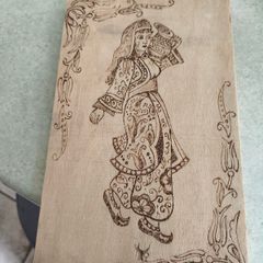 a piece of wood art featuring a pyrography (wood-burning) design of a woman in traditional attire.