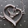A silver bracelet with a heart-shaped pendant featuring a horse and foal's head. Image 9