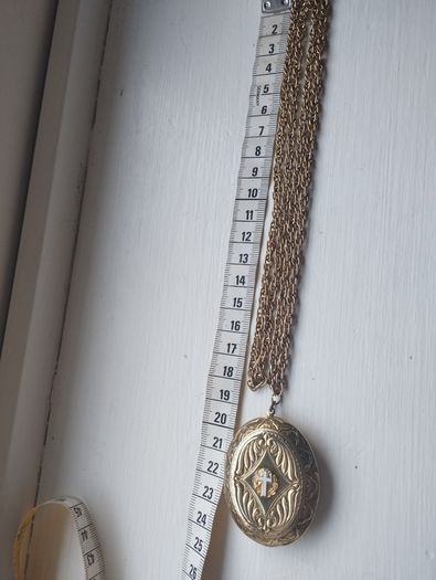 A large medallion featuring religious symbols, suspended from a long chain.