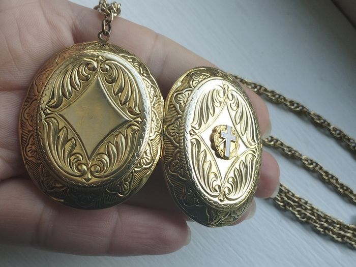 A large medallion featuring religious symbols, suspended from a long chain.