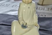 Porcelain Boy with Candle Nao by Lladro, depicting a seated child in a white nightshirt holding a small candle, postage available or collection