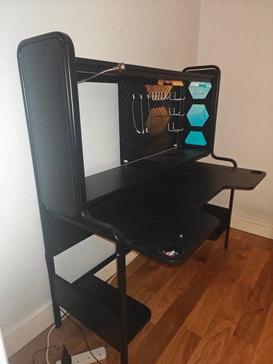 Black gaming desk with integrated pegboard and shelf