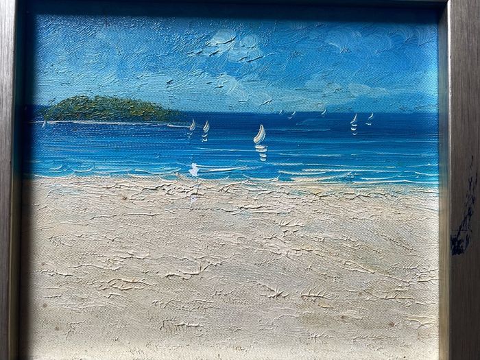 original impasto oil painting on canvas depicts a sunny coastal beach scene with sailboats on the water and a headland in the background