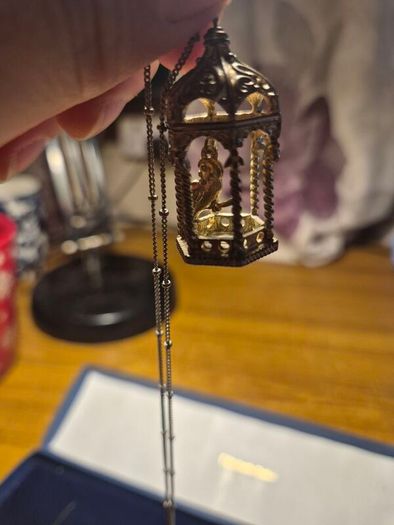 Vintage gilded bird cage with a bird pendant.