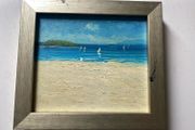 original impasto oil painting on canvas depicts a sunny coastal beach scene with sailboats on the water and a headland in the background