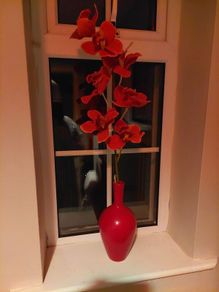 Pretty red vase with single artificial flower stem