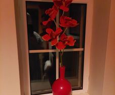 Pretty red vase with single artificial flower stem