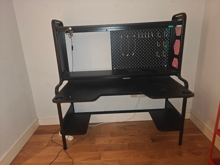 Black gaming desk with integrated pegboard and shelf