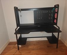 Black gaming desk with integrated pegboard and shelf