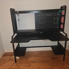 Black gaming desk with integrated pegboard and shelf