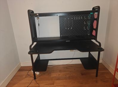 Black gaming desk with integrated pegboard and shelf