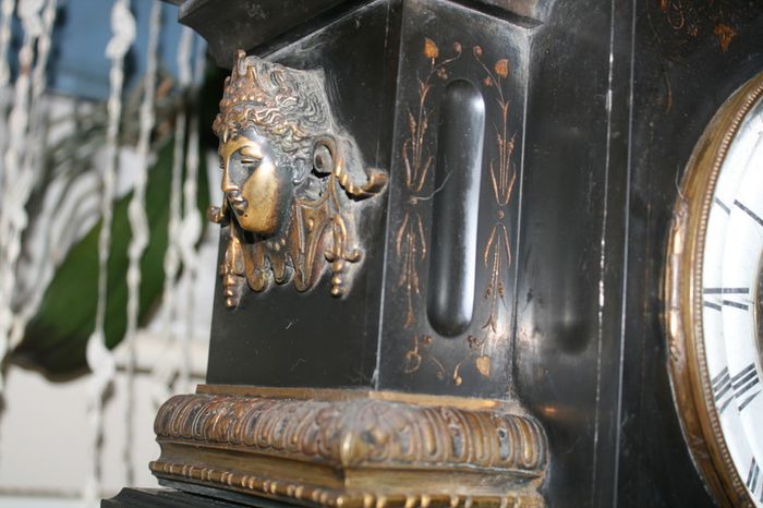 Victorian French Black Slate Mantle Clock (Very large and heavy) with bronze ornamentation Oversized. Open escarpment slate plate Roman numerals. Circa 1890s. Accented with Trojan head. Flanked by two Hellenistic ladies heads on sides. Rose cartouche mask