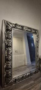 Ornate silver-finished wall mirror with a baroque style carved frame featuring deep acanthus leaf and swirling scroll motifs.