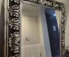 Ornate silver-finished wall mirror with a baroque style carved frame featuring deep acanthus leaf and swirling scroll motifs.
