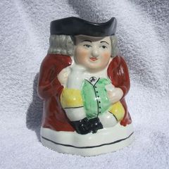 An antique TOBY JUG (Staffordshire potteries) - a seated toby holding his ale jug and cup (late 19th century). Excellent condition. About 14cm height.