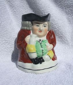 An antique TOBY JUG (Staffordshire potteries) - a seated toby holding his ale jug and cup (late 19th century). Excellent condition. About 14cm height.
