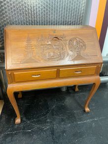 This is a vintage mid-20th-century Asian carved wood writing bureau featuring an intricate hand-carved traditional landscape on the drop-front lid.