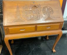 This is a vintage mid-20th-century Asian carved wood writing bureau featuring an intricate hand-carved traditional landscape on the drop-front lid.