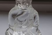 A glass Buddha figurine seated in the lotus position.