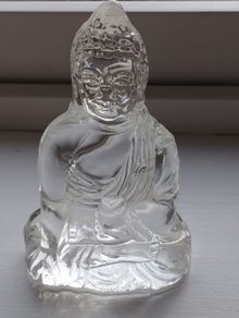 A glass Buddha figurine seated in the lotus position.