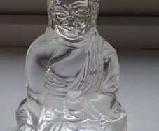 A glass Buddha figurine seated in the lotus position.