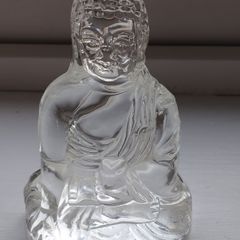 A glass Buddha figurine seated in the lotus position.