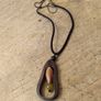 wooden pendant necklace featuring a dark brown wooden frame, a light-colored central bead, and a small dark yellow stone accent on an adjustable braided cord. Image 2