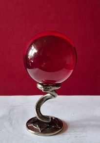 Red crystal/glass ball and metal serpent stand.