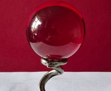 Red crystal/glass ball and metal serpent stand.