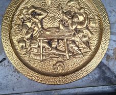 Large Brass Wall Charger Old World Pub Scene, Embossed Tavern scene of 17th-century Pubs. This is a striking brass wall hanging, with an Old World pub scene. It is pressed hammered brass. The raised relief image features a pair of men in Old World dress, 