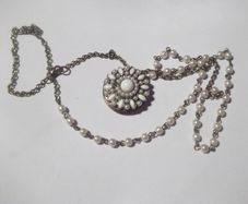 a vintage locket  penden on a long chain with pearls and white stones