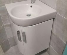 Corner wall hung vanity unit, sink and tap.